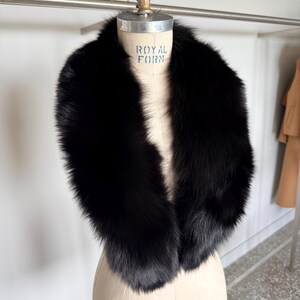 May include: A luxurious black fur collar displayed on a mannequin. The collar is thick and plush, with a deep, rich black color. The mannequin is a neutral beige color, and the background is a bright white.