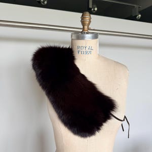 May include: A dark brown fur collar displayed on a vintage dress form. The collar is a rich, deep shade, with a soft, textured appearance. The dress form has the text "ROYAL FORM" printed on it.