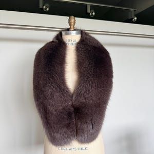 以下が含まれることがあります： ヴィンテージのマネキンに展示された、豪華なダークブラウンの毛皮の襟。 襟は厚く、柔らかく、深く豊かな色をしています。 マネキンは明るいベージュ色で、「COLLAPSIBLE MODEL 2000」と書かれています。