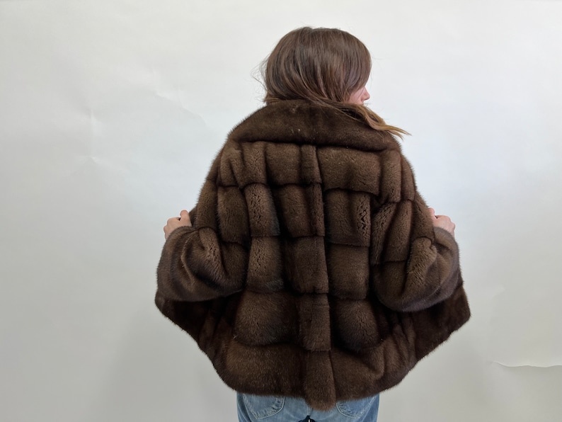 K&ouml;nnte beinhalten: Eine braune Pelzjacke mit einer kurzen L&auml;nge und einem Kragen. Die Jacke ist aus weichem, luxuri&ouml;sem Pelz gefertigt und hat einen klassischen, eleganten Stil.