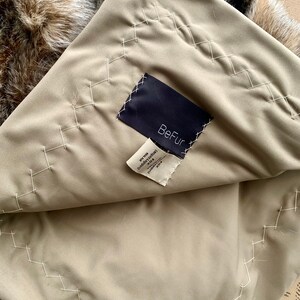 Pode incluir: Um forro de tecido bege com uma etiqueta preta que diz "BeFur" e uma etiqueta branca com o texto "Faux Fur (Angora turco) 100% Poli&eacute;ster Fabricado na China"