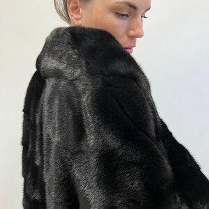 May include: A black fur coat with a long sleeve and a high collar.