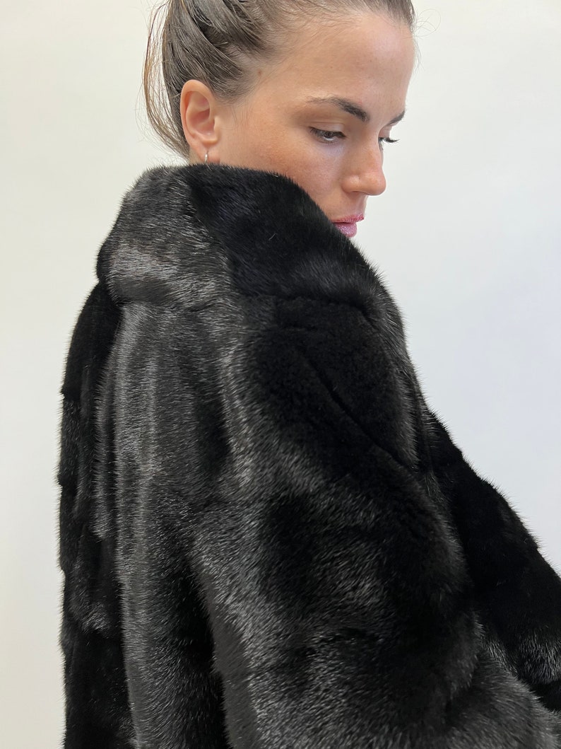 May include: A black fur coat with a long sleeve and a high collar.
