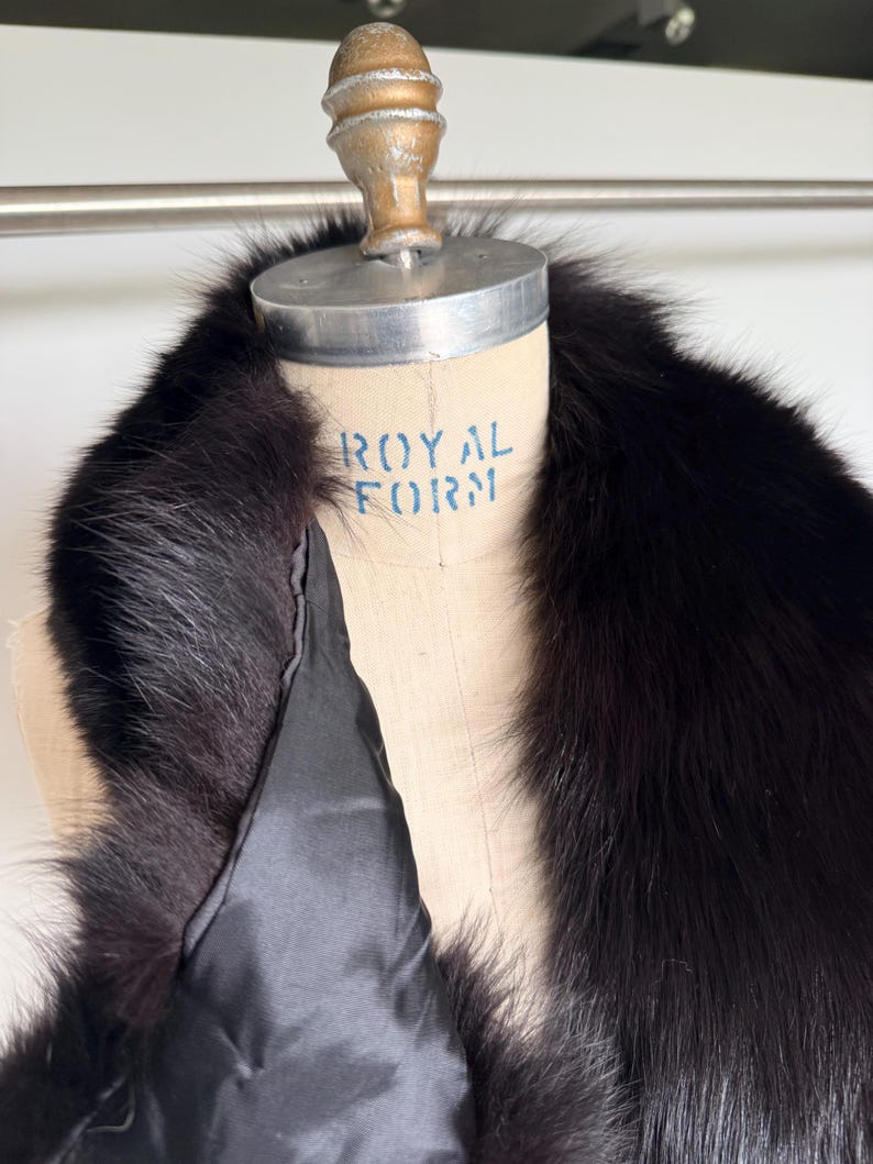 May include: A luxurious black fur collar with a satin lining. The collar is displayed on a mannequin with the words "ROYAL FORM" printed on it. The fur appears soft and plush, with a deep, rich color.