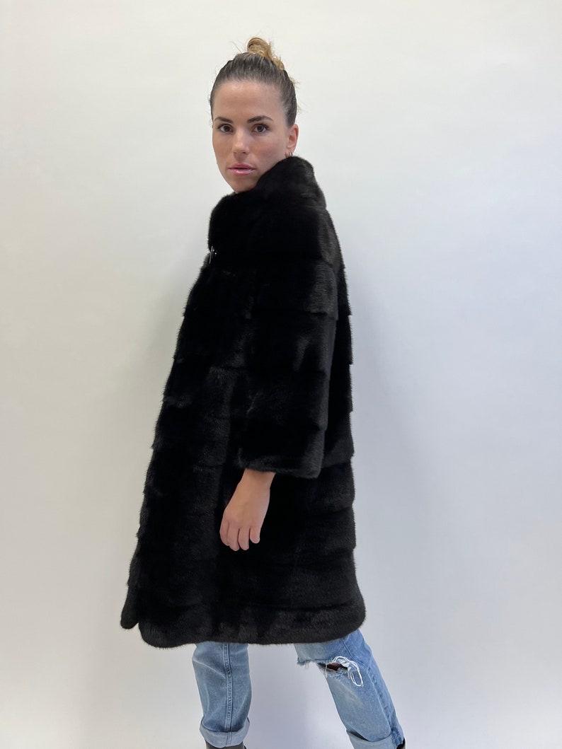 May include: A black fur coat with a high collar and a long, straight silhouette. The coat is made of soft, luxurious fur and has a sleek, modern design.