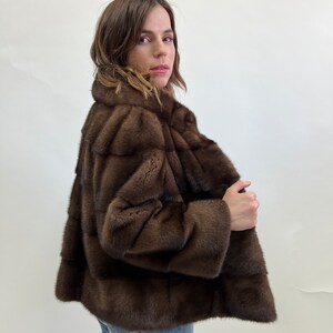 K&ouml;nnte beinhalten: Eine braune Pelzjacke mit Stehkragen. Die Jacke ist aus weichem, luxuri&ouml;sem Pelz gefertigt und hat ein klassisches, zeitloses Design.