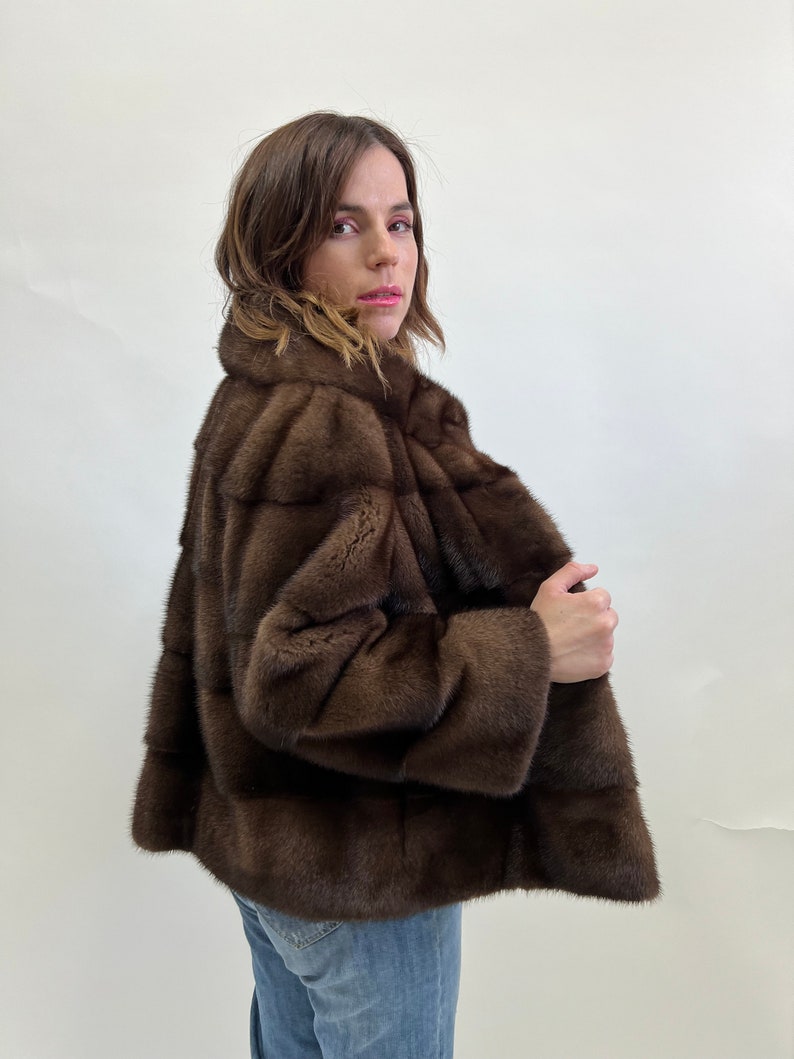 K&ouml;nnte beinhalten: Eine braune Pelzjacke mit Stehkragen. Die Jacke ist aus weichem, luxuri&ouml;sem Pelz gefertigt und hat ein klassisches, zeitloses Design.
