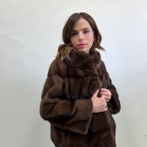 K&ouml;nnte beinhalten: Eine braune Pelzjacke mit Stehkragen und Knopfleiste. Die Jacke ist aus weichem, luxuri&ouml;sem Pelz gefertigt und hat einen klassischen, eleganten Stil.