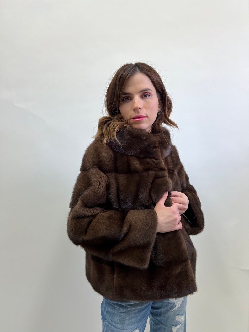 K&ouml;nnte beinhalten: Eine braune Pelzjacke mit Stehkragen und Knopfleiste. Die Jacke ist aus weichem, luxuri&ouml;sem Pelz gefertigt und hat einen klassischen, eleganten Stil.