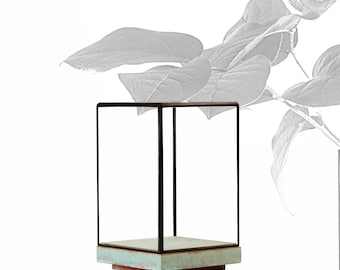 May include: A black metal display case with a light blue base. The case is empty and has a square shape.