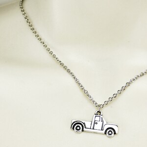 Op de afbeelding: Een zilveren ketting met een zilveren pick-up truck bedel.