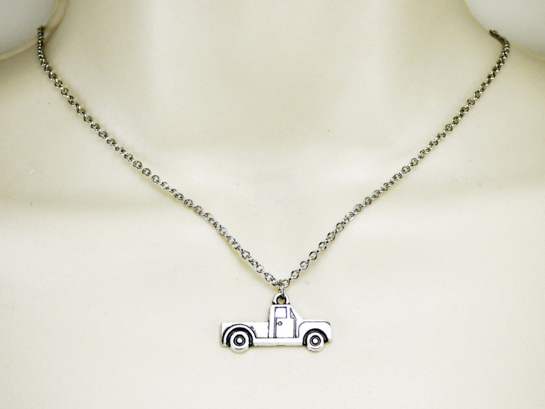 Op de afbeelding: Een zilveren ketting met een zilveren aanhanger in de vorm van een pick-up truck.