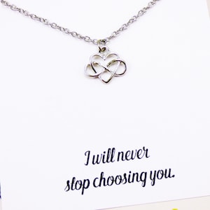 Puede incluir: Un collar de plata con un dije en forma de corazón infinito. El collar viene con una tarjeta que dice "Nunca dejaré de elegirte."