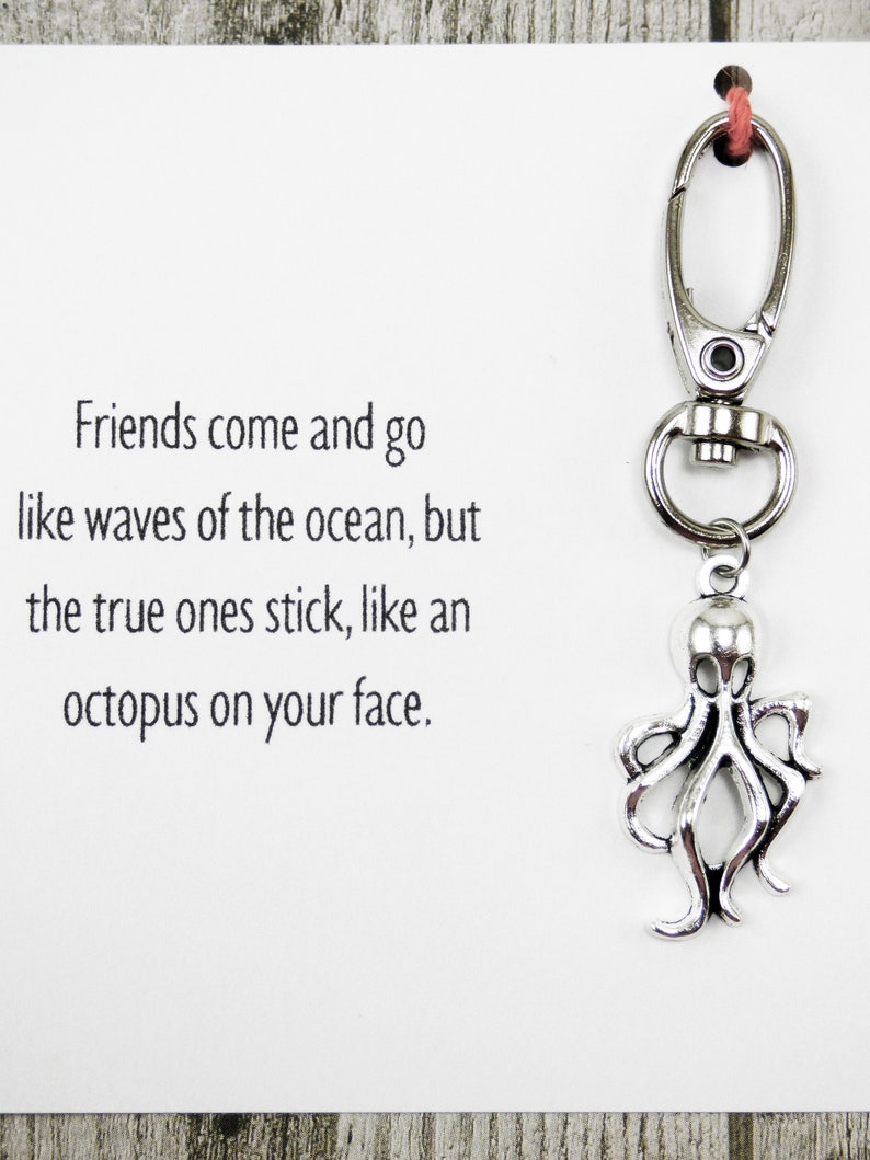 May include: A silver octopus keychain with a quote that reads "Friends come and go like waves of the ocean, but the true ones stick, like an octopus on your face."