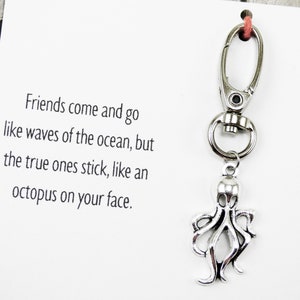 May include: A white card with the text "Friends come and go like waves of the ocean, but the true ones stick, like an octopus on your face."  A silver octopus charm is attached to a silver key chain.