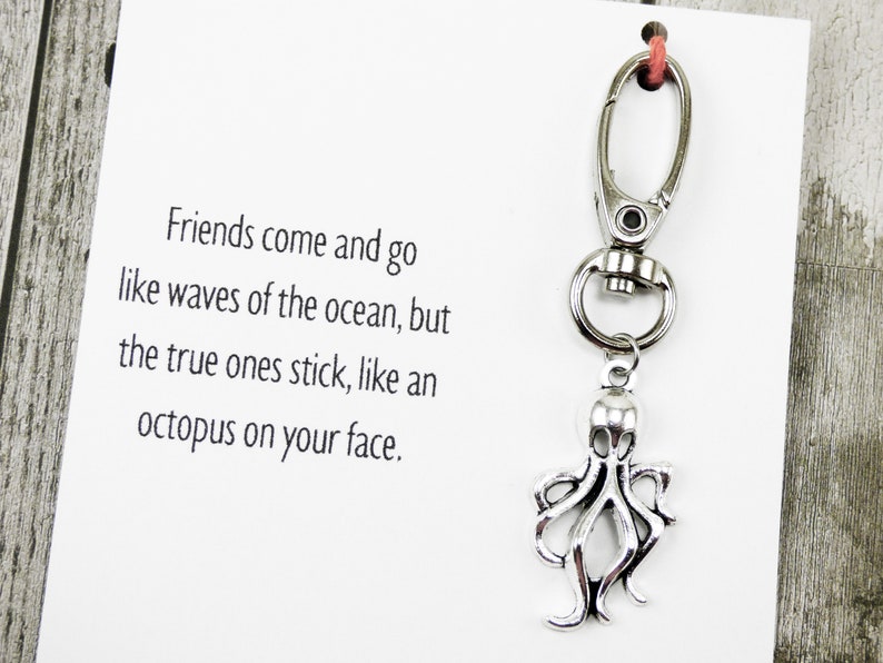 May include: A white card with the text "Friends come and go like waves of the ocean, but the true ones stick, like an octopus on your face."  A silver octopus charm is attached to a silver key chain.