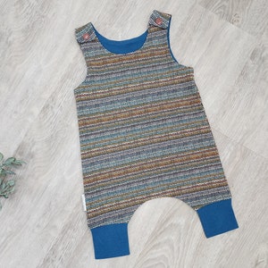 May include: A blue and brown striped baby overall with blue trim. The overall has a sleeveless design and two brown buttons on the straps.