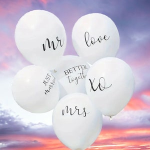 May include: White balloons with black lettering, reading "mr", "love", "better together", "xo", and "mrs", against a sunset sky.