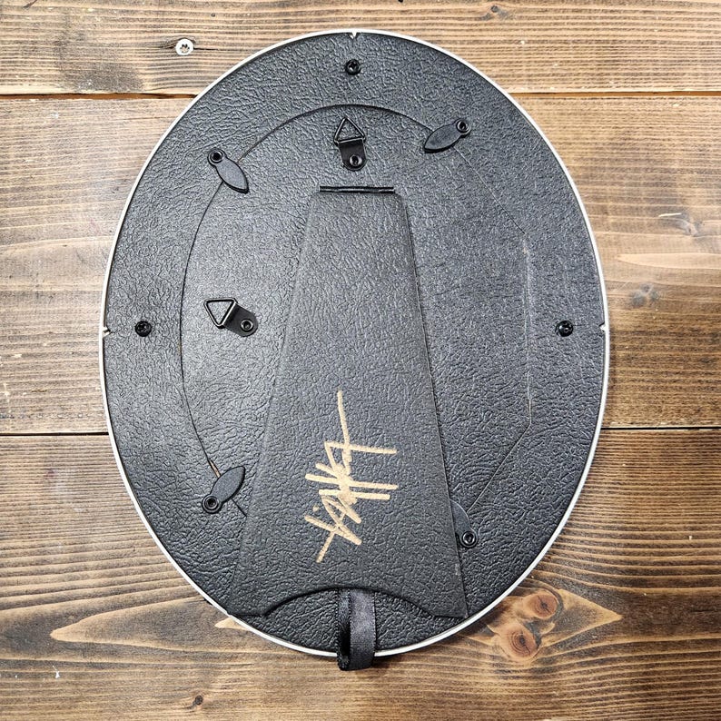 Peut inclure: Un cadre photo ovale noir avec un logo dor&eacute; "Stussy" au dos. Le cadre est dot&eacute; d'un crochet de suspension au dos.