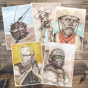 May include: Set of five watercolor art prints featuring characters and scenes from a post-apocalyptic setting. The prints showcase a variety of figures, including a robot, cowboys, and soldiers, with a desert backdrop and a vintage aesthetic.