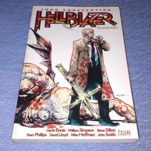 May include: A comic book titled "Hellblazer: Bloodlines" featuring a character in a trench coat holding a cross. The cover art depicts a battle scene with a monster and blood splatter. The book's title is in red and black.
