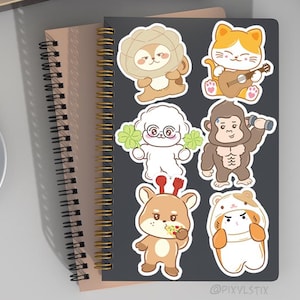 May include: A set of seven colorful stickers featuring cartoon animals. The animals include a lion, a cat playing a guitar, a poodle, a gorilla, a deer, and two hamsters. The stickers are on a black background.