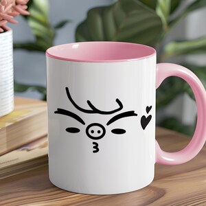 May include: White ceramic mug with a pink rim and handle. The mug features a black and white illustration of a pig face with a winking eye and a heart.