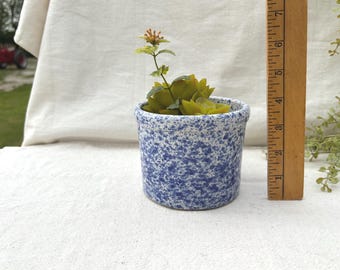 Asa falta el asa del pequeño recipiente de cerámica azul y blanca con forma de esponja.