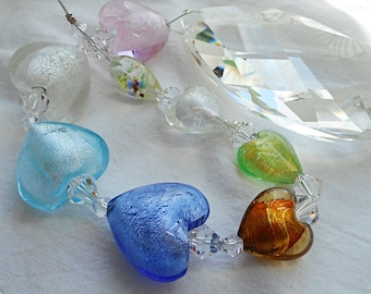 Big crystal prism on a string of hearts in pastel colours. Colourful suncatcher, elegant design for window décor.