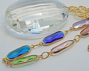 Long suncatcher with an oval prism and faceted glass and brass decoration. A colourful gift for a window accent, an any occasion gift.