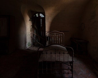Chiaroscuro photography of a bed in an arched room, in an abandoned chapel in France