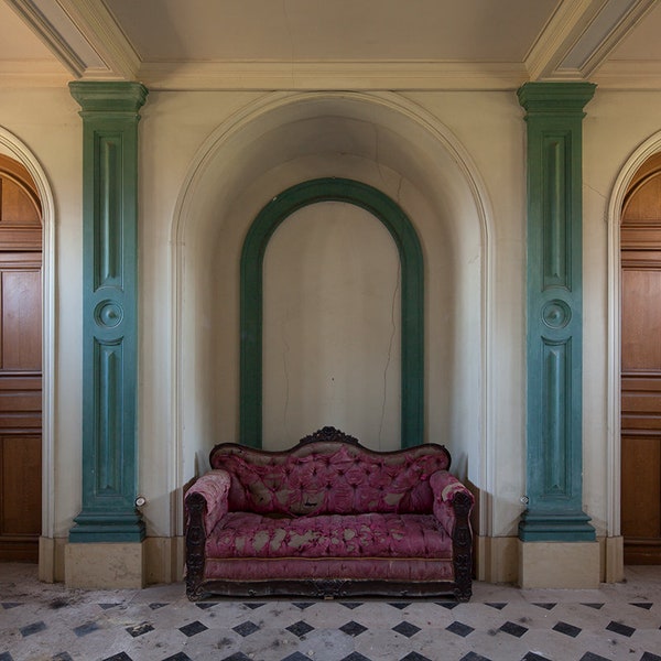 Photographie d'un canapé rose dans un château abandonné en France