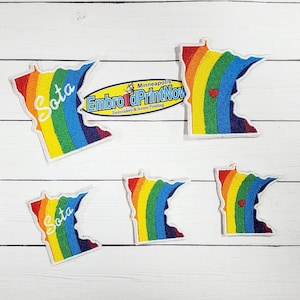 May include: Five rainbow-colored Minnesota state outline patches with white stitching. Two patches have the word "Sota" in white text. One patch has the text "Embro & PrintNow" in black text with the words "Minneapolis" and "Embroidery & Screen Printing" in smaller text below.