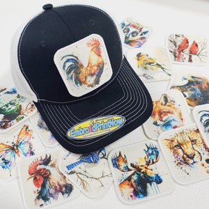 May include: A black and white trucker hat with a white square patch featuring a colorful rooster illustration. The hat is surrounded by various colorful patches with animal and nature illustrations, including a fox, a moose, a butterfly, a cheetah, a blue jay, a cardinal, a goldfinch, a lemur, a rooster, and a Yoda character.