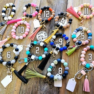 May include: Twelve colorful beaded keychains with a metal ring and a tassel. Each keychain has a number from 1 to 12.