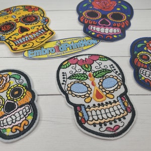May include: Five colorful embroidered sugar skull patches. The skulls are decorated with flowers, leaves, and other details. The patches are perfect for adding a touch of Mexican culture to your clothing, bags, or other accessories.