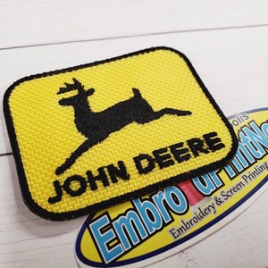 May include: Yellow and black embroidered patch with a stylized deer and the text "JOHN DEERE".
