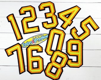 May include: A set of iron-on patches featuring the numbers 0 through 9 in a yellow and orange color scheme with black outlines. The patches are designed in a varsity style font.