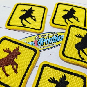 May include: Five yellow square patches with black borders and a moose silhouette in the center.  The moose are in different poses and some are brown.  The patches are for sale by the company "Pro Print Now" in Minneapolis.