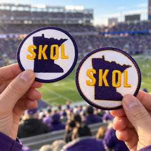 May include: Two circular embroidered patches featuring a white background with a purple silhouette of the state of Minnesota. The word SKOL is stitched in bold yellow letters across the center of each patch, which are finished with a purple border.