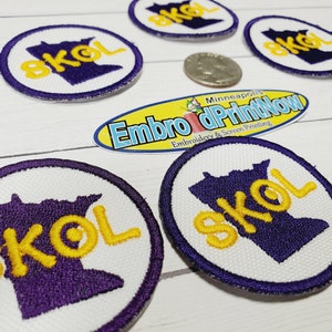 May include: Eight embroidered patches with the word "SKOL" in yellow lettering on a purple outline of the state of Minnesota. The patches are circular and have a white background with a purple border.