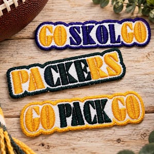 May include: Three rectangular embroidered patches with scalloped edges. The top patch features yellow text reading GO SKOL GO in purple. The middle patch features yellow text reading PACKERS in dark green. The bottom patch reads GO PACK GO in yellow.