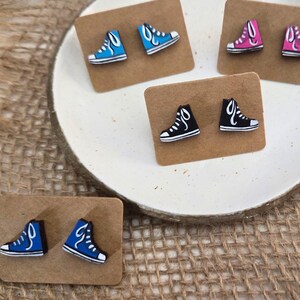 May include: Six pairs of colorful shoe-shaped earrings on brown card stock. The shoes are in blue, pink, black, and red.