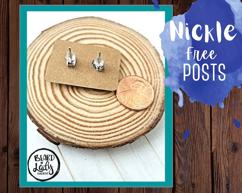 May include: A pair of silver stud earrings on a brown wooden surface with a penny for scale. The earrings are nickel free and the text "Beard Lady Handmade" is visible in the lower left corner.