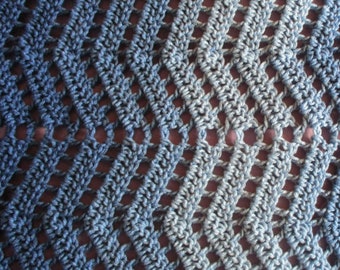 May include: Close-up of a crocheted fabric with a diamond pattern in shades of blue and gray.