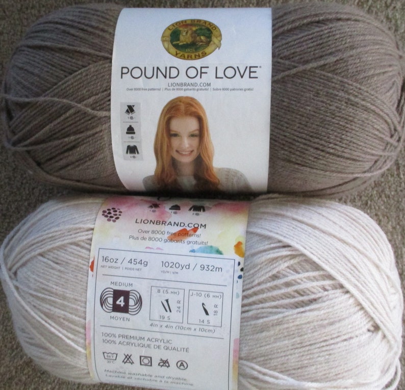 Może przedstawiać: Dwa motki wł&oacute;czki Lion Brand Pound of Love. Jedna motka jest jasnobrązowa, a druga jasnobeżowa. Etykieta informuje, że wł&oacute;czka jest w 100% akrylowa i nadaje się do prania i suszenia w pralce.