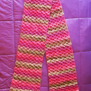 May include: A pink and brown crocheted scarf with a diagonal pattern.