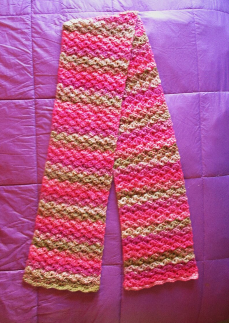 May include: A pink and brown crocheted scarf with a diagonal pattern.