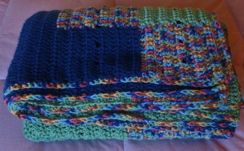 May include: A multi-colored crocheted blanket with blue, green, brown, and red stripes. The blanket is made of a soft, textured yarn and has a fringed edge.