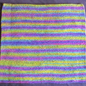 May include: A knitted blanket with a striped pattern in shades of purple, green, blue, and pink.